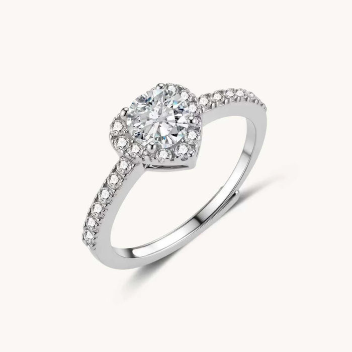 Heart-shaped halo ring with brilliant moissanite center stone surrounded by smaller crystals in sterling silver setting