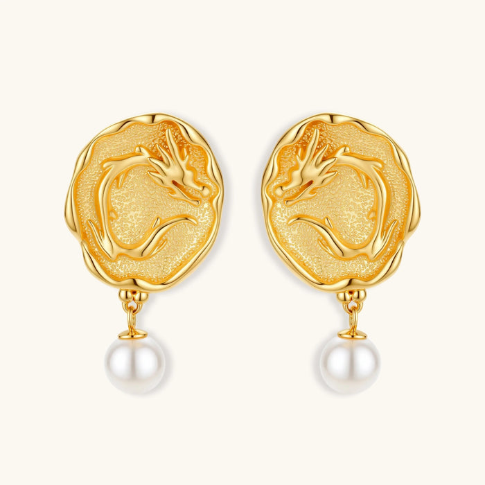 Ornate gold-plated dragon medallion earrings with white shell pearl drops on beige background, featuring detailed Chinese motifs.