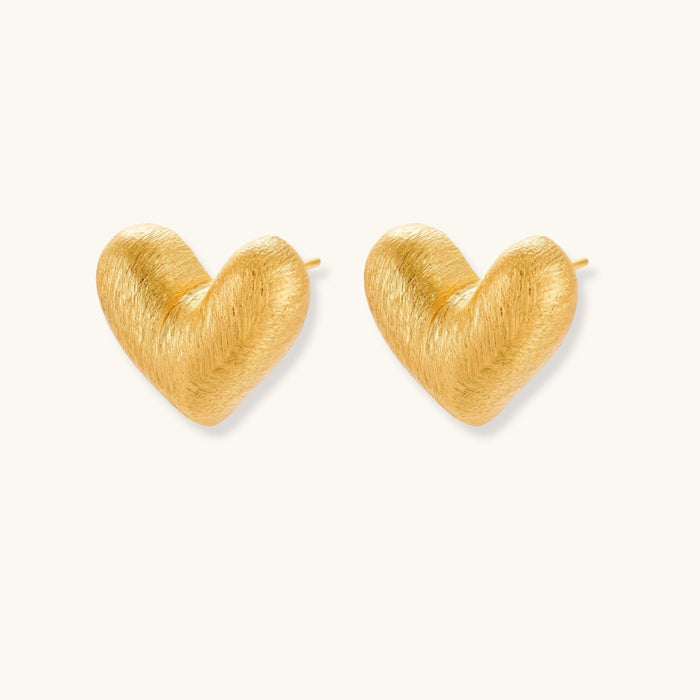 Pair of small heart-shaped stud earrings with brushed metallic finish, showing both silver and gold variants on neutral background.
