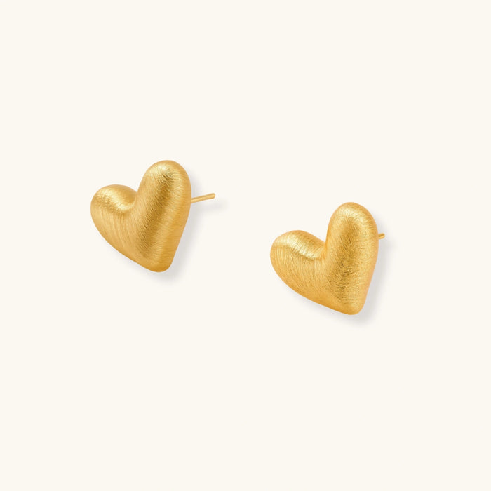 Pair of small heart-shaped stud earrings with brushed metallic finish, showing both silver and gold variants on neutral background.